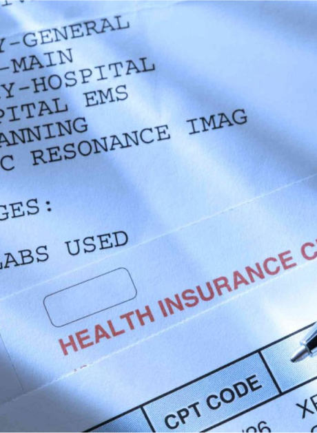 Close-up of a health insurance claim form showing CPT codes and various medical services like hospital imaging. A section labeled "Health Insurance" is highlighted in red, and the page is illuminated by natural lighting.