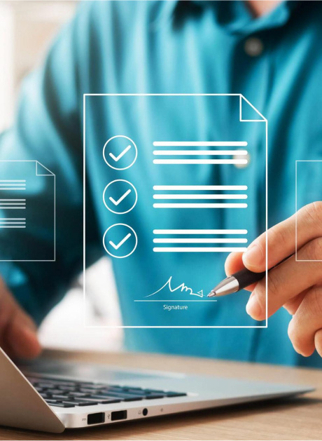 A person in a blue shirt uses a pen to digitally sign a virtual document displayed over a laptop. The document shows a checklist with checked items.